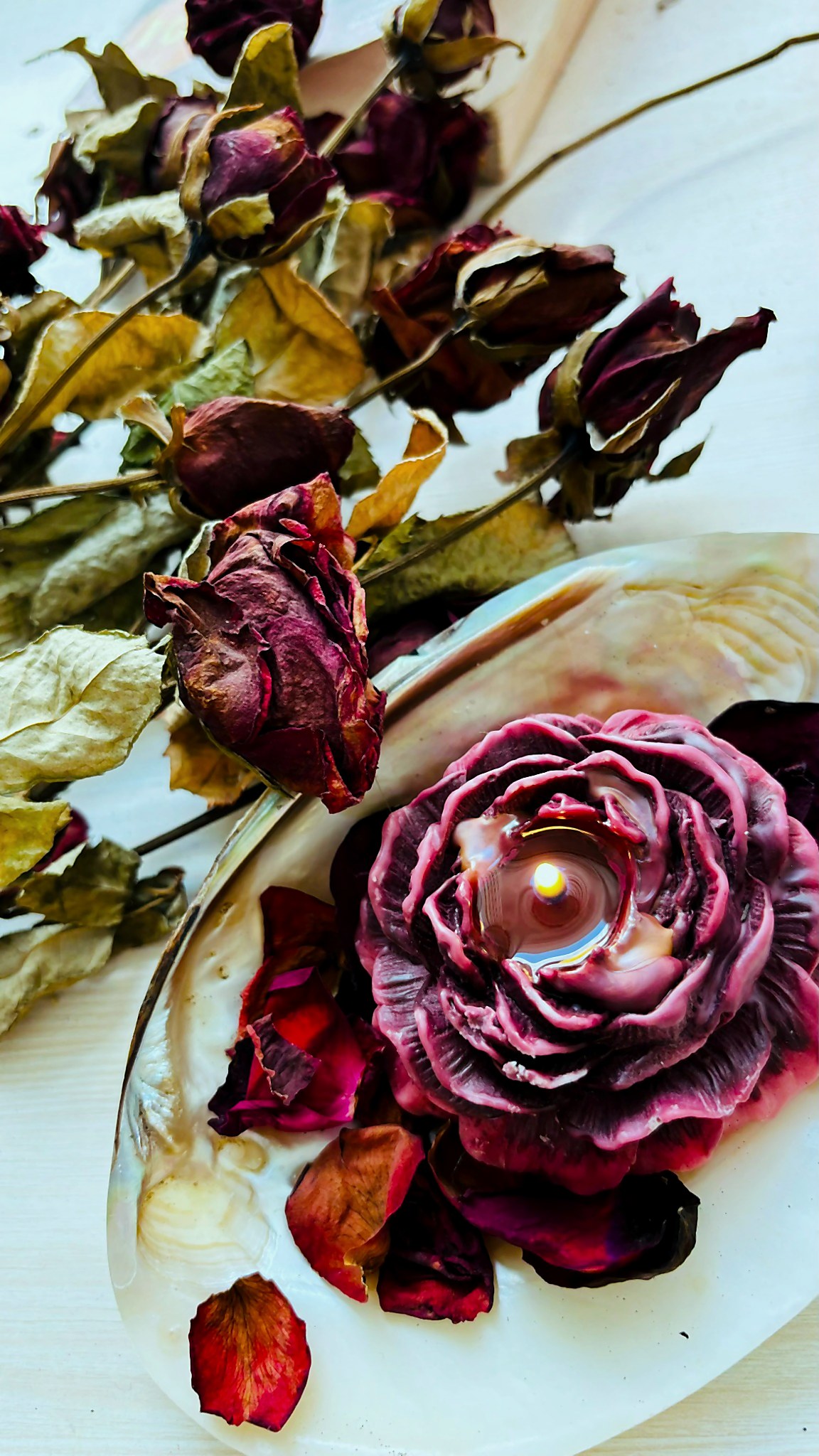 A close-up of a candle whose top has been sculpted into a full dried rose